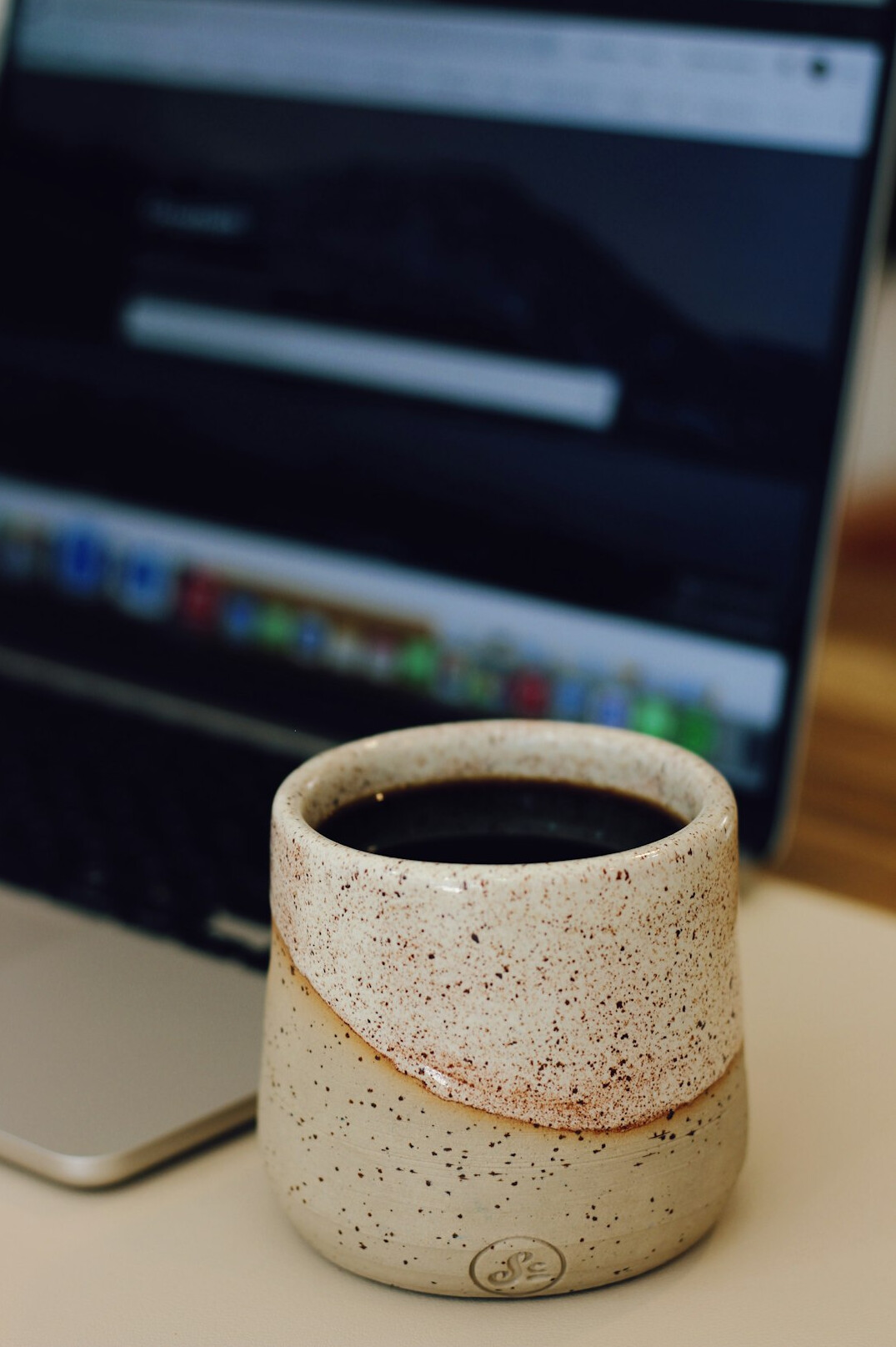Laptop displaying an email inbox mockup on a wooden desk with a coffee cup